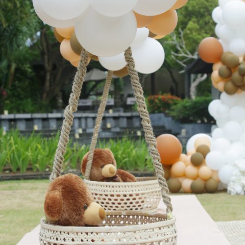 Teddy bear decoration. Creative gender neutral baby shower or birthday decoration in the garden. White cream peach caramel bohemian style outdoor event set up with balloons.